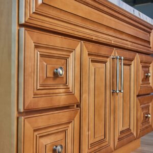 Wooden kitchen cabinet with ornate paneling and metal handles.
