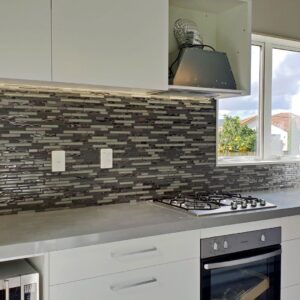Modern kitchen with gray tile backsplash and stainless steel appliances.