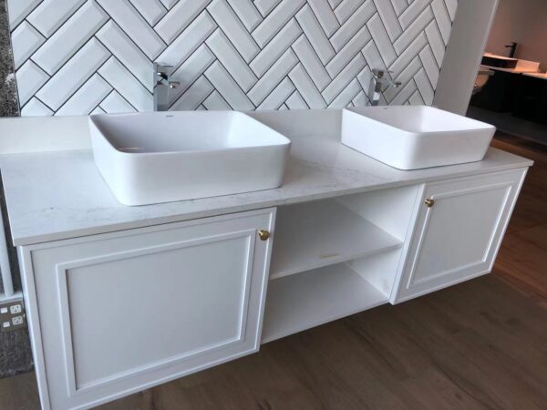 Modern white bathroom vanity with two sinks and herringbone tile backsplash.